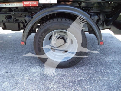 Rear wheel with fender and spare tire showing 'NO FORKS' sign and metal truck frame undercarriage.