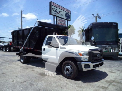 Ford F550 roll-off truck in a used condition showing white cab and black dump bed with signs in background.
