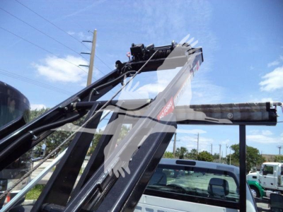 Ford F550 roll-off truck arm and hydraulic crane visible with blue sky
