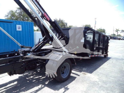 Ford F-550 roll-off truck chassis with hydraulic crane arm and dumping trailer in service view showing wheel and hydraulic components.