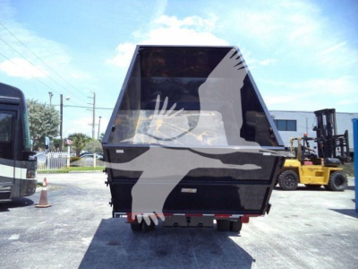 Truck bed with roll-off dumpster attachment on a Ford F-550 rear view showing hydraulic lift and back of the container.