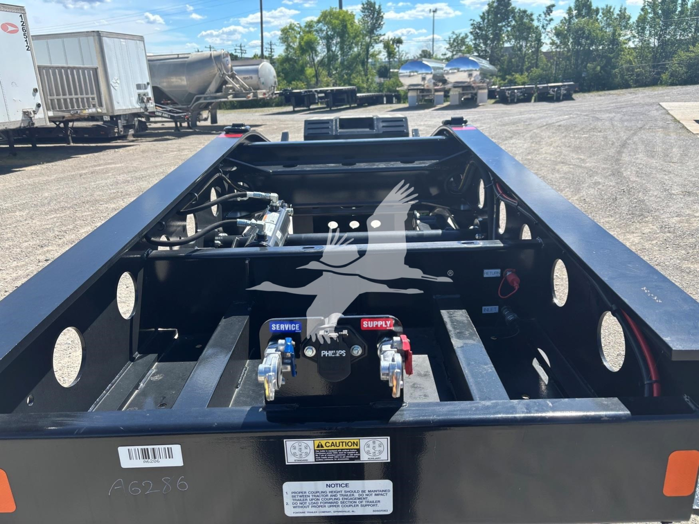 Lowboy trailer frame with visible hydraulic and electrical components, storage area, and warning labels; Fontaine Renegade N20 trailer under construction.