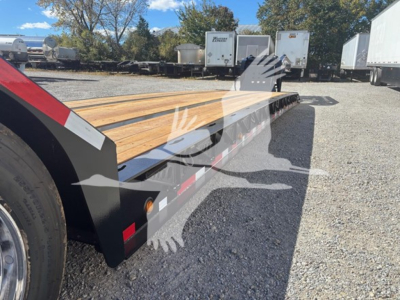  Fontaine lowboy trailer with wooden deck and pony motor area showing side rails and wheel in foreground.