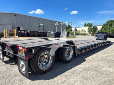 Fontaine Renegade N20 lowboy trailer showing triple-axle configuration, aluminum deck, and rear lights. Branding and model not fully legible; site shows industrial yard.