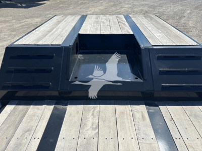 Flatbed trailer platform with a central cutout and side ramps, wooden deck planks and black steel frame, Fontaine Renegade N20 trailer component visible.