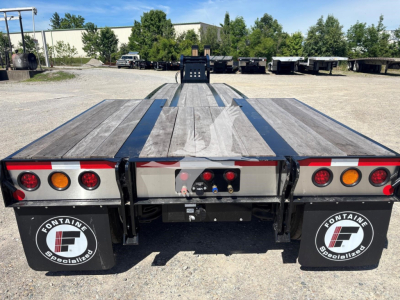 Flatbed trailer rear view showing wooden deck with center stripe, taillights, mud flaps with Fontaine Specialized logo, and rear bumper hardware.
