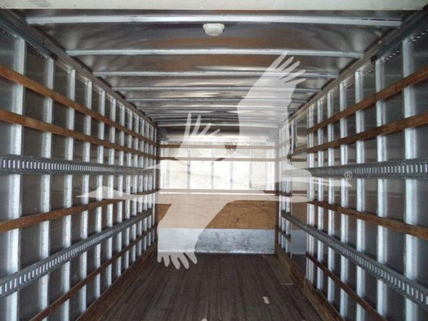 Truck interior showing empty box truck with metal side rails and wooden floor, viewed from rear doors.