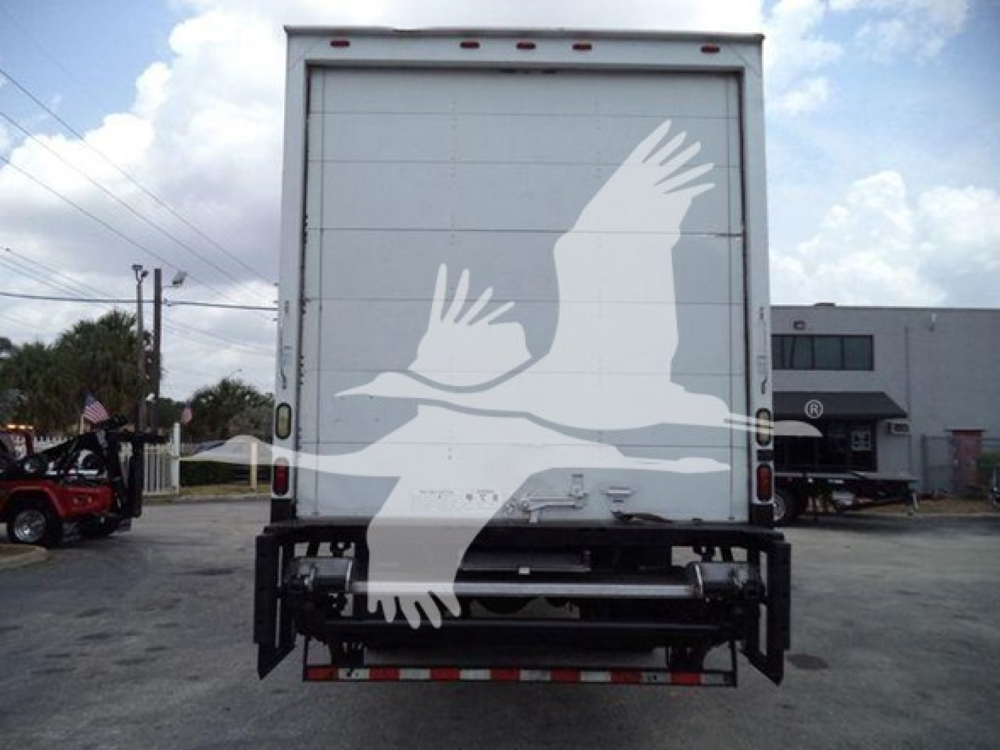 Rear view of a Mack MD7 box truck showing a large graphic of white birds on the back doors, with bumper and underride guard visible.