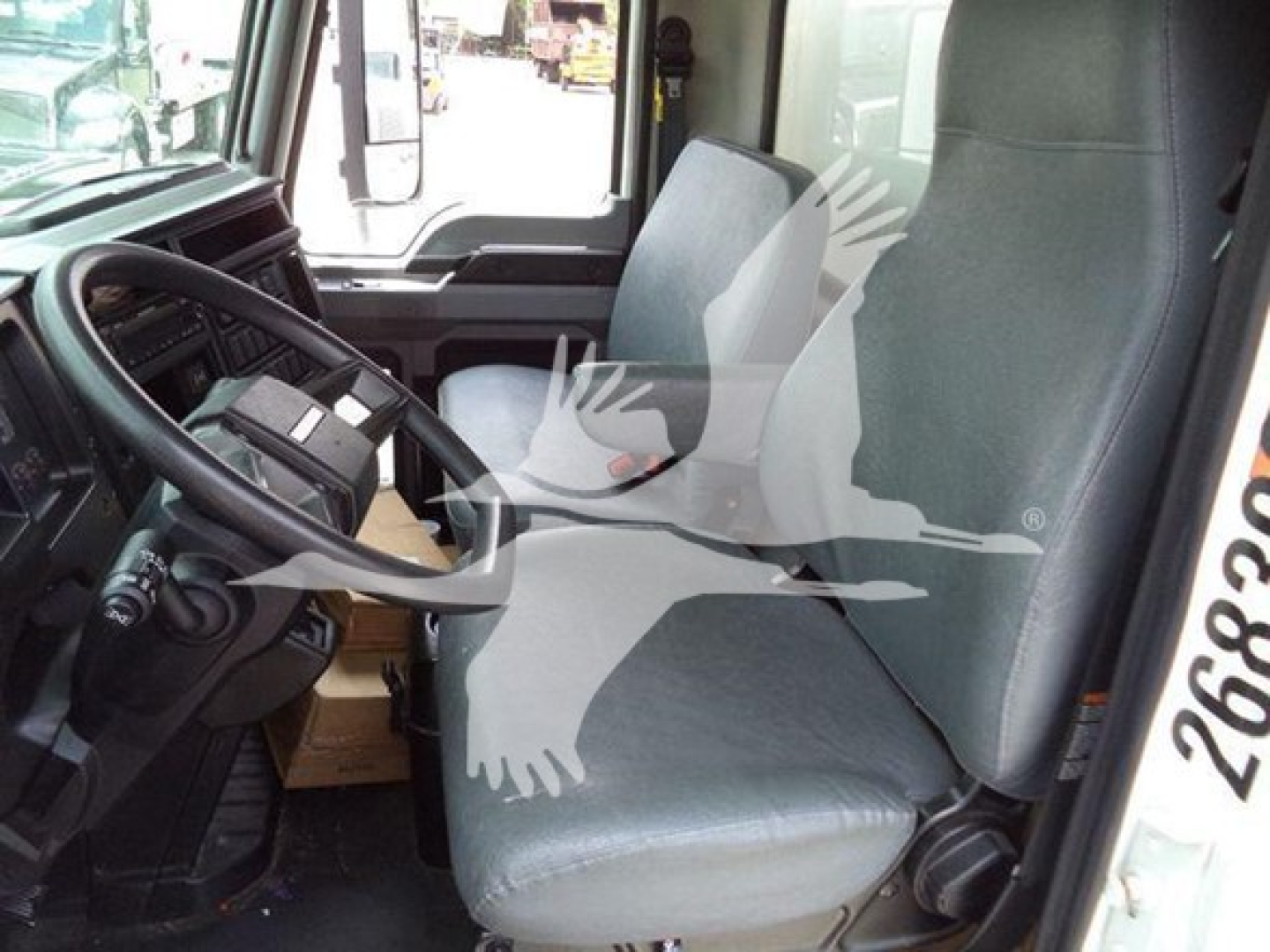 Cab interior of a Mack MD7 truck showing driver's seat and dashboard with steering wheel.