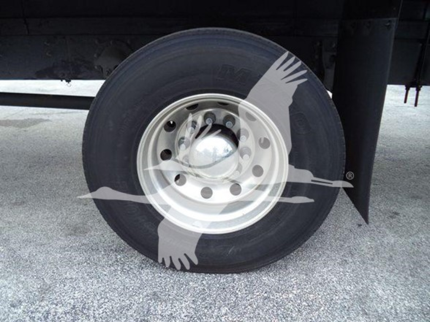 Dually wheel/tire on Mack MD7 truck chassis showing steel rim and tire tread with hubcap and mudflap.