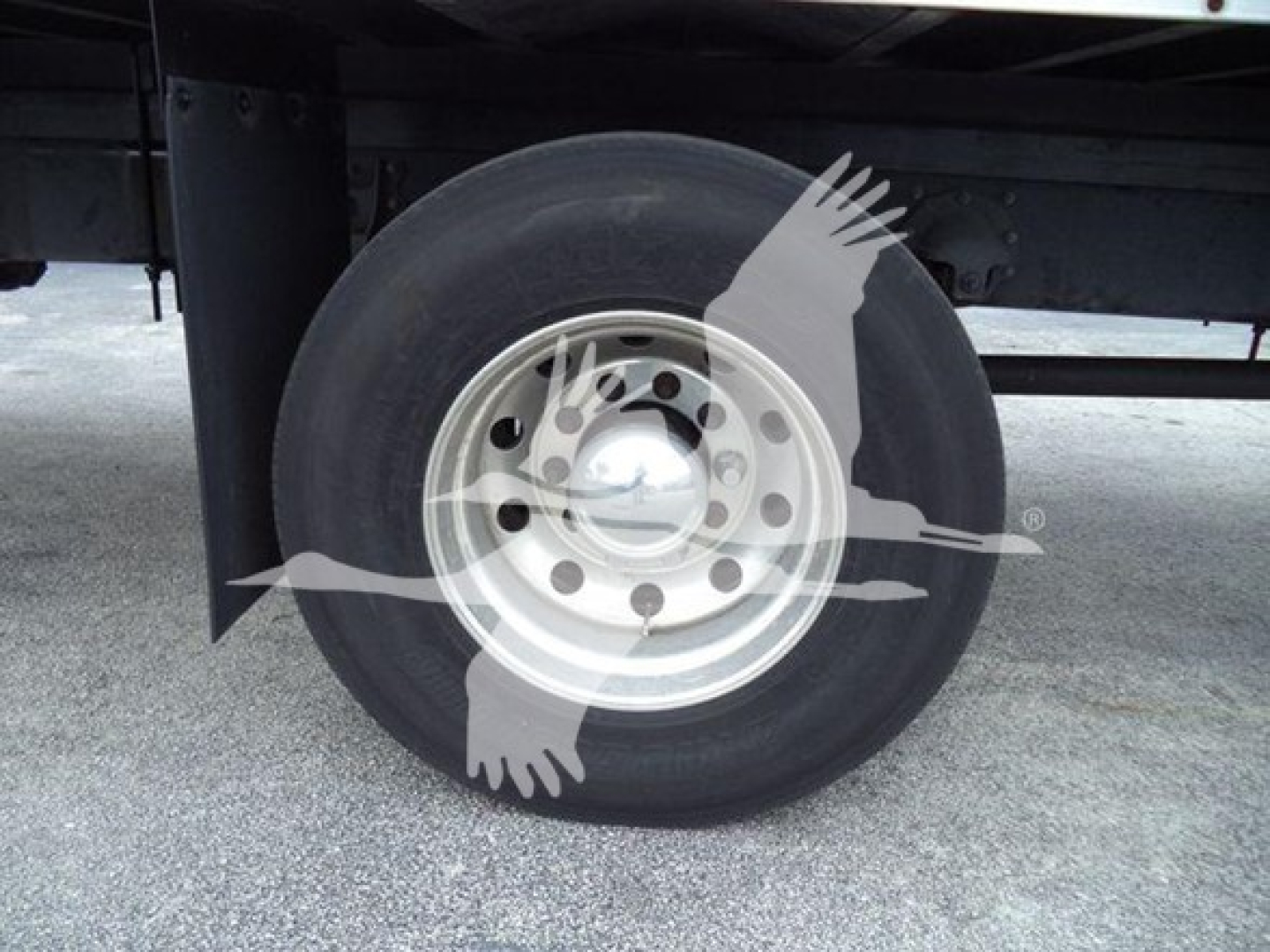 Truck wheel and tire on Mack MD7 chassis showing single rear wheel with steel hub and dual rear axle? image shows wheel with hubcap and black tire; partial undercarriage visible.