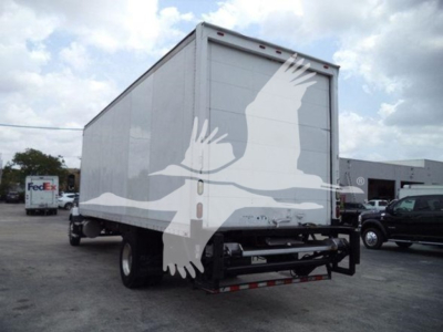 Box truck rear view showing large bird silhouette artwork on back doors and closed trailer with FedEx truck in background