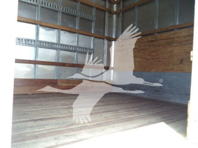 Truck interior cargo area of a 2023 Mack MD7 box truck with empty wooden floor and metal walls.