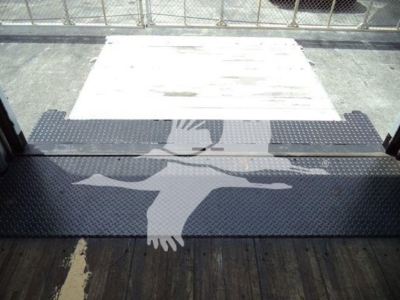 Mack MD7 truck cargo area entry step with textured diamond plate surface and tailgate; platform shows loading area with metal ramp and black grip mats.