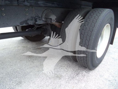 Truck axle and dual tires undercarriage view with leaf springs and frame; visible components include rear axle housing, suspension, and tire tread.