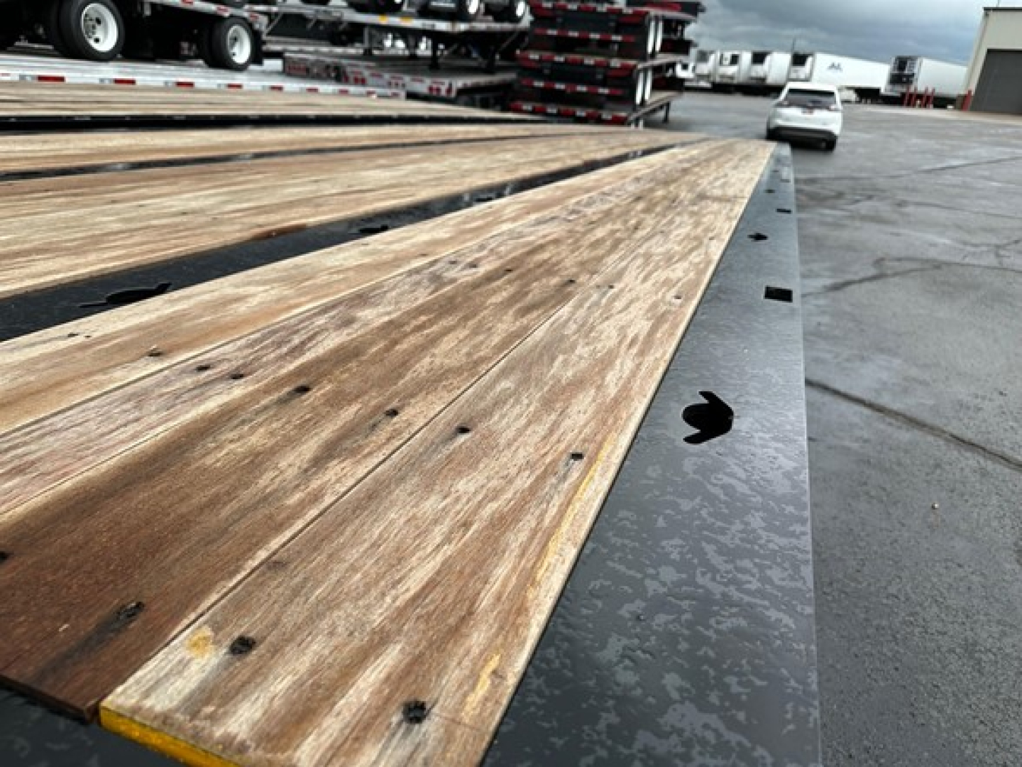 Trailer bed with wooden planks and black metal edge, Edge has round holes and bolts; part of a Trail-Eze TE801 trailer.