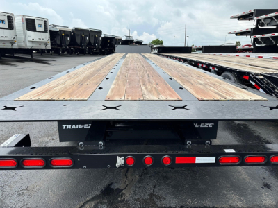 Trail-Eze TE801 trailer flatbed with wooden deck, rear view showing taillights and 8-8 markings, in a truck yard.
