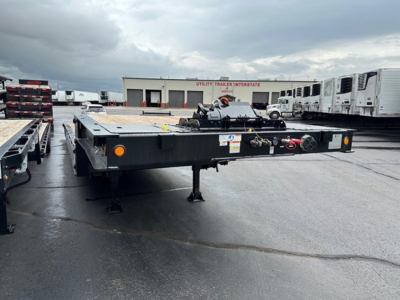 Trailer TE801 traveling axle flatbed trailer with hitch and ramps in an open lot.