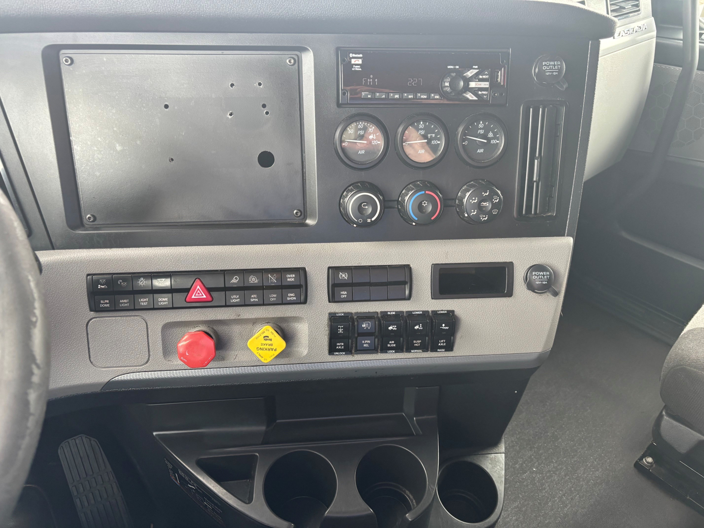 Cab interior of a Freightliner CA-126 showing instrument cluster, control switches, and cup holders in the dashboard area.
