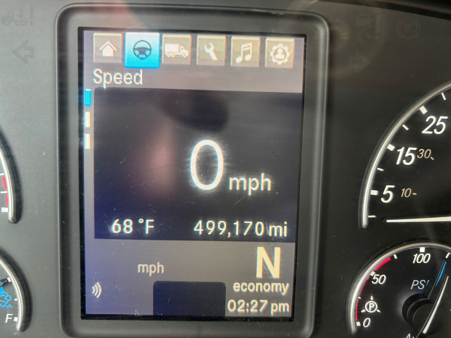 Dashboard display showing speed 0 mph, 68°F outside temperature, 499,170 miles, gear N, and economy indicator in a Freightliner truck cab.