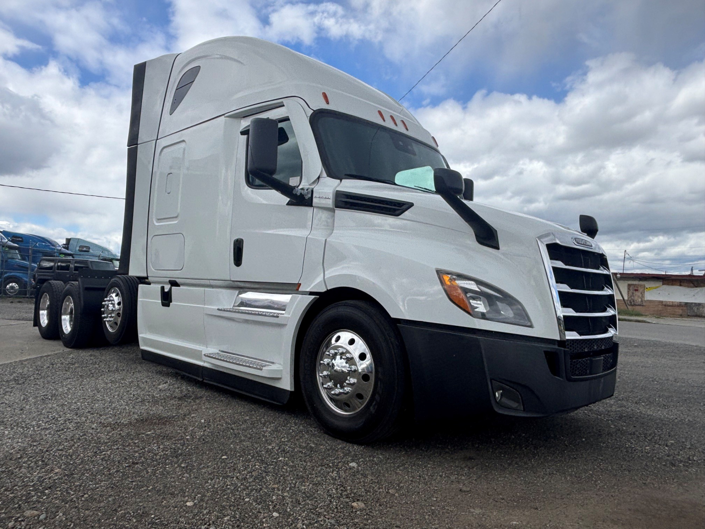 Freightliner highway tractor cab in white, front-right view showing sleeper cab, chrome wheels, and aerodynamic mirrors.