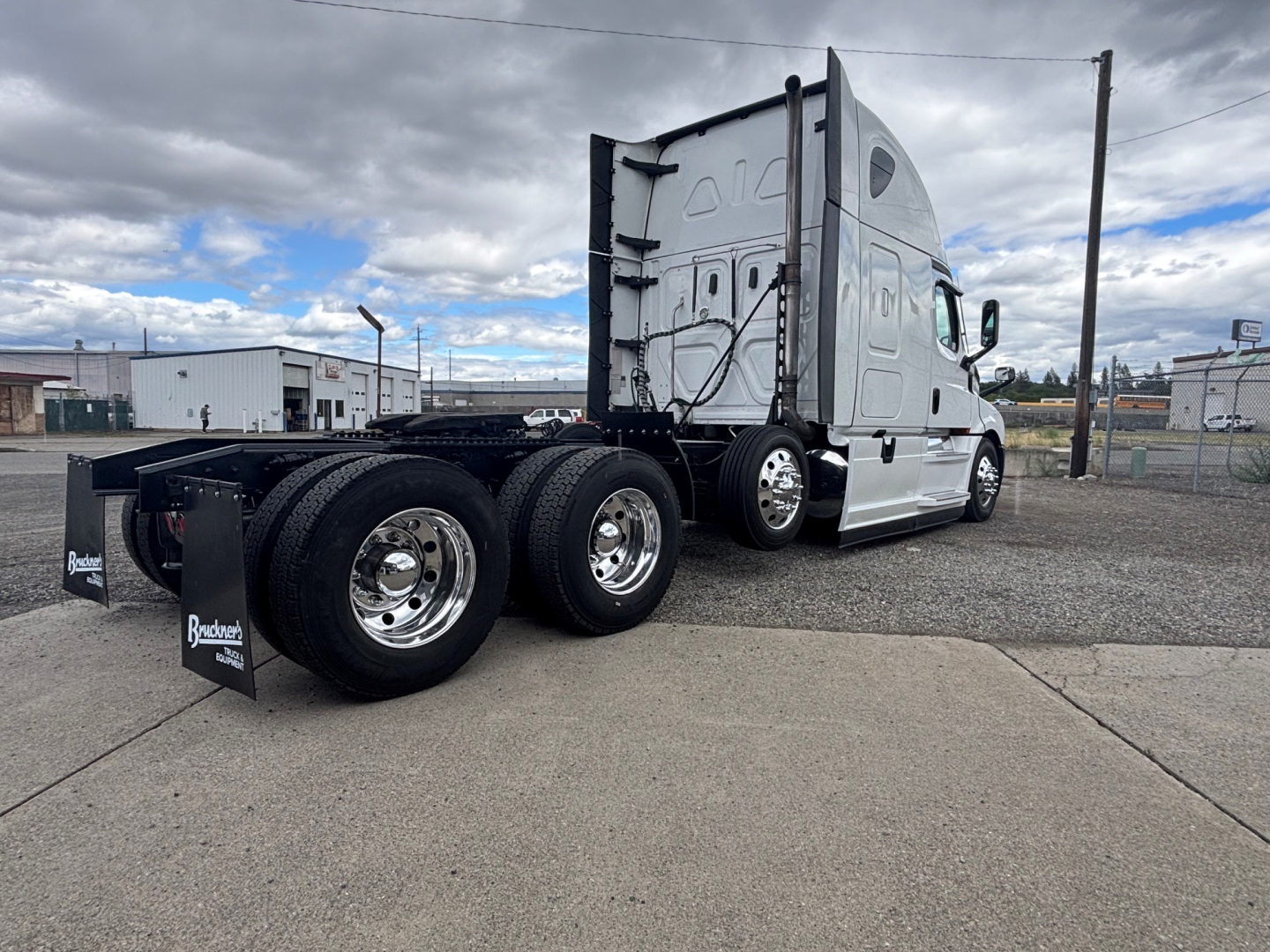 Freightliner CA-126 conventional sleeper truck rear-side view showing dual rear axles and aluminum wheels with black fenders.