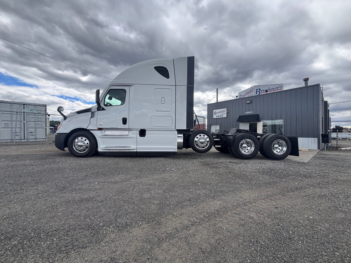 Truck cab and dual rear axle tractor from a Freightliner CA-126, white cab with sleeper, side view showing fuel tanks and chassis.