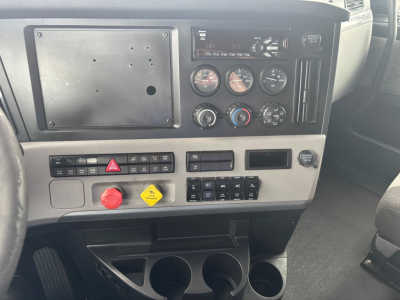 Cab interior of a Freightliner CA-126 showing instrument cluster, control switches, and cup holders in the dashboard area.