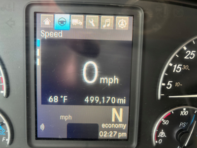Dashboard display showing speed 0 mph, 68°F outside temperature, 499,170 miles, gear N, and economy indicator in a Freightliner truck cab.