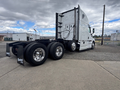 Freightliner CA-126 conventional sleeper truck rear-side view showing dual rear axles and aluminum wheels with black fenders.