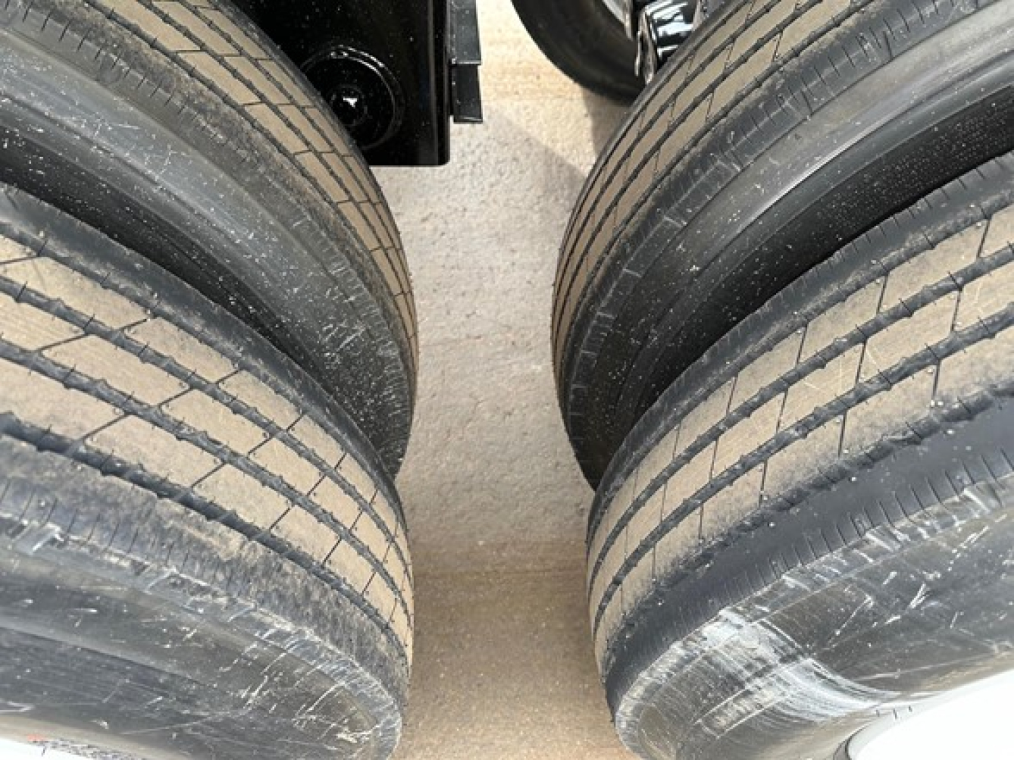 Trailer tires close-up view showing dual axle dual tires with tread grooves and road grime on a light cargo trailer.