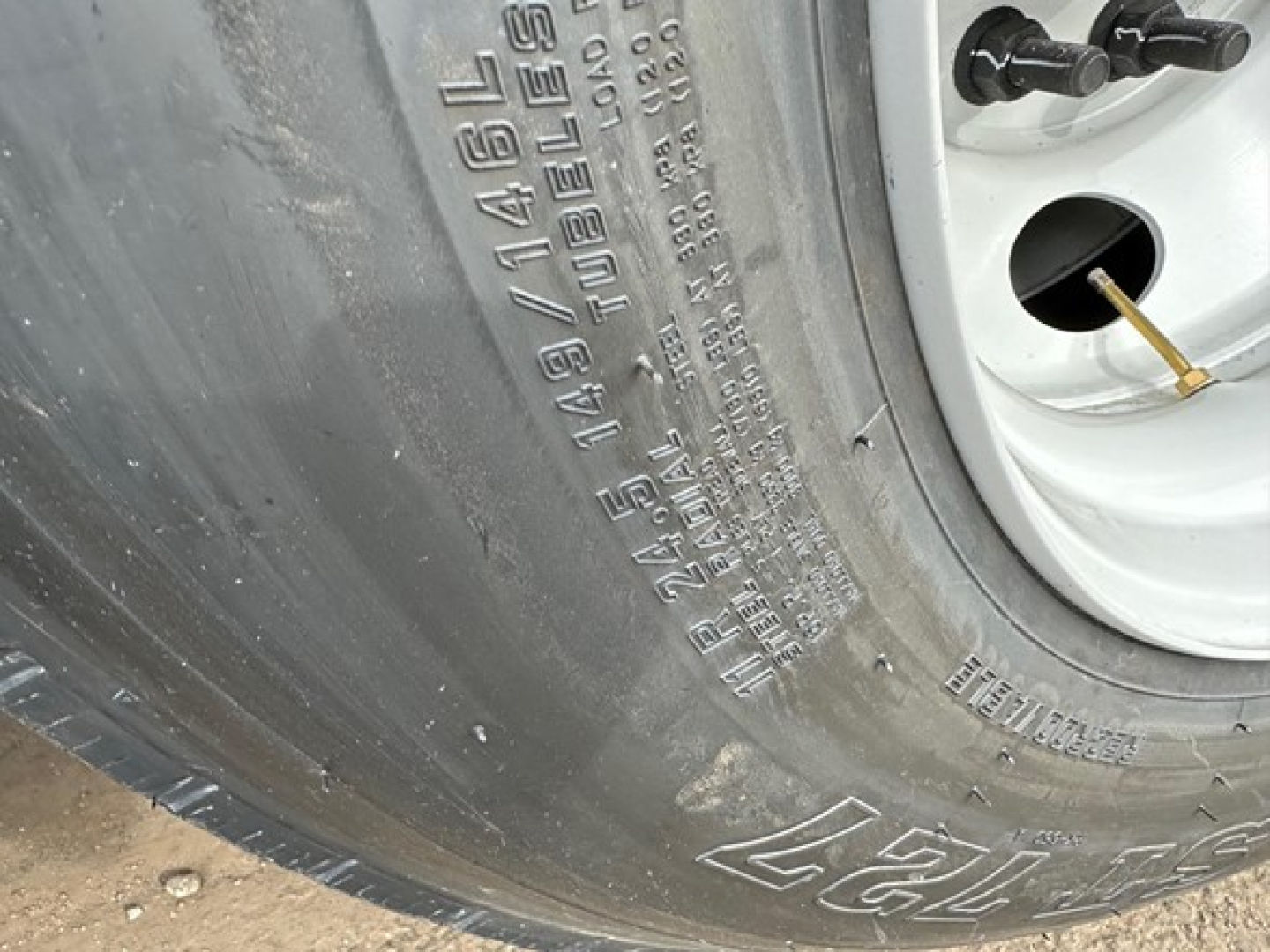 Tire sidewall with embossed tire specifications and a wheel well; visible text includes PLY: 14/50 and various load/size markings.