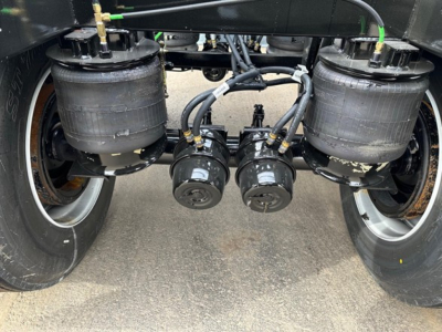 Trailer view showing dual air tanks and two central air lines with hoses under a bottom dump unit.