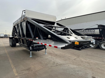 Dump trailer with black frame and aluminum side rails showing electric hydraulic bottom dump mechanism and support legs.