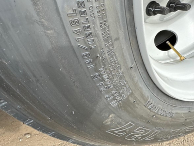 Tire sidewall with embossed tire specifications and a wheel well; visible text includes PLY: 14/50 and various load/size markings.