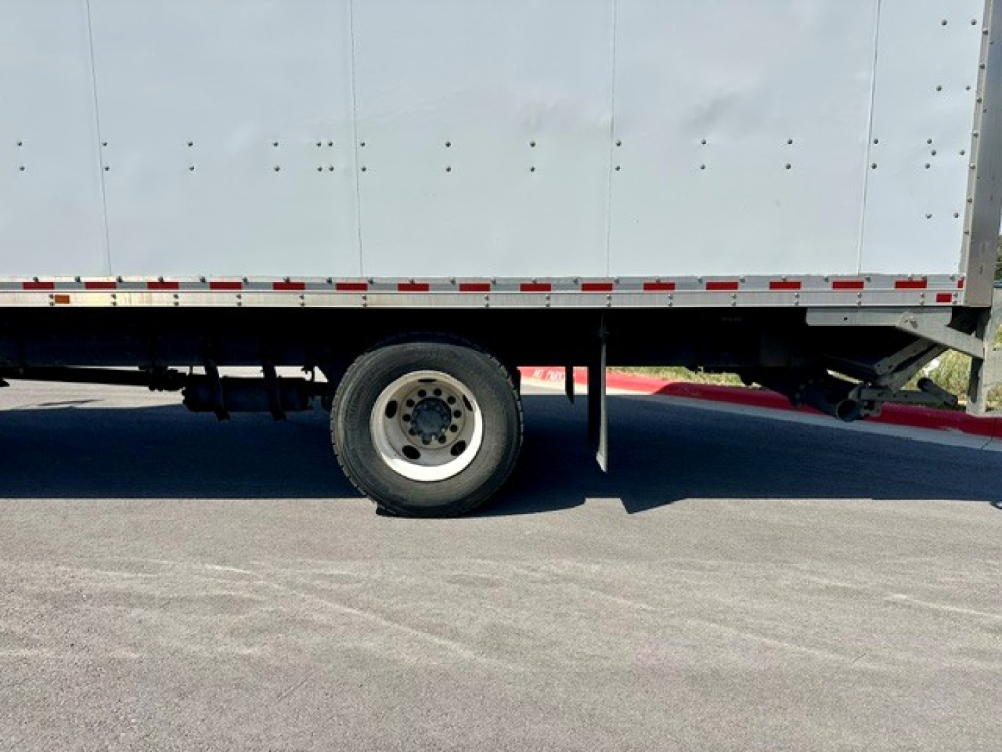 Freightliner M2-106 side view showing box truck rear wheel and undercarriage.