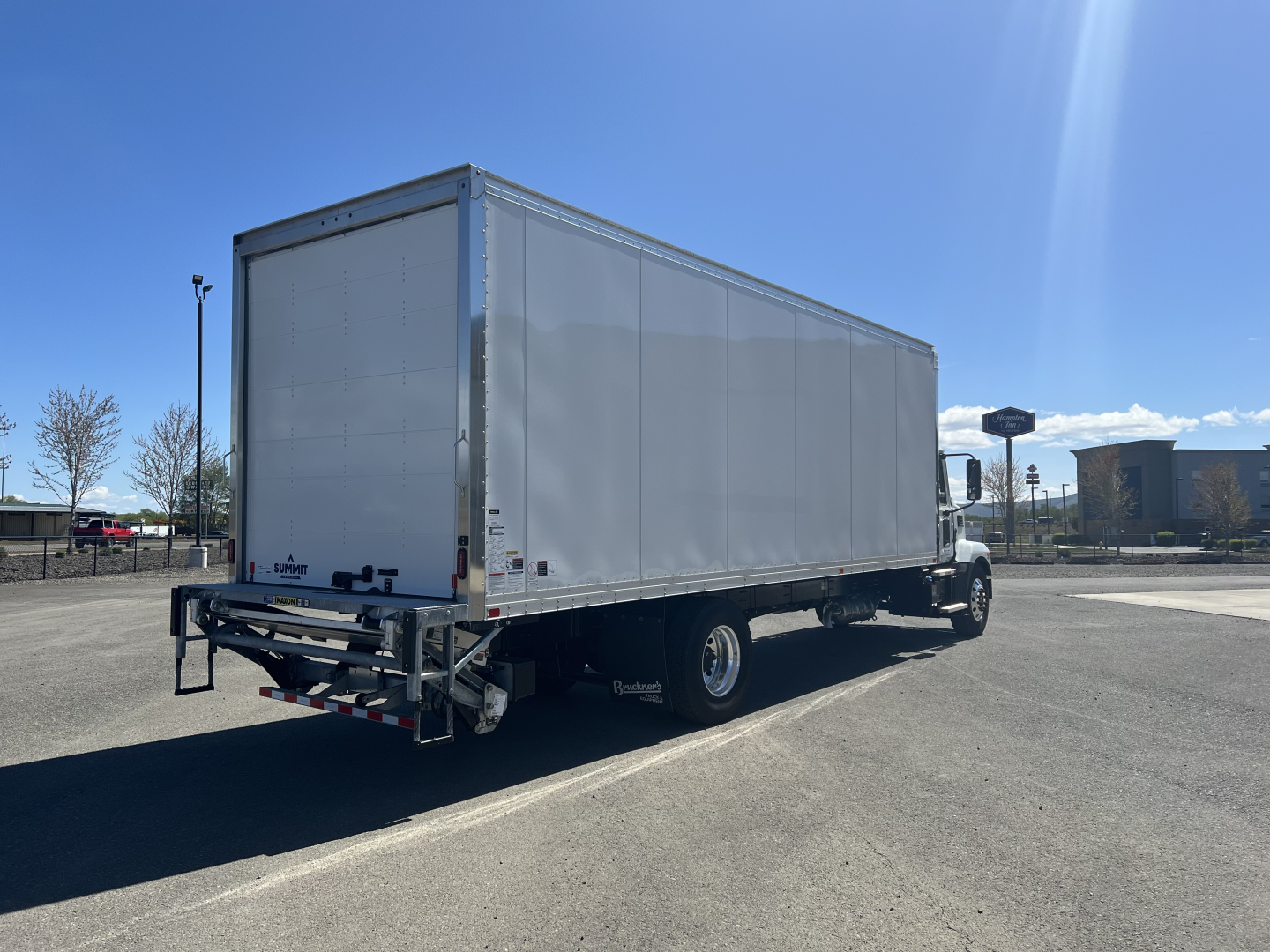Mack MD6 box truck rear-left view showing cargo box and chassis with tires.