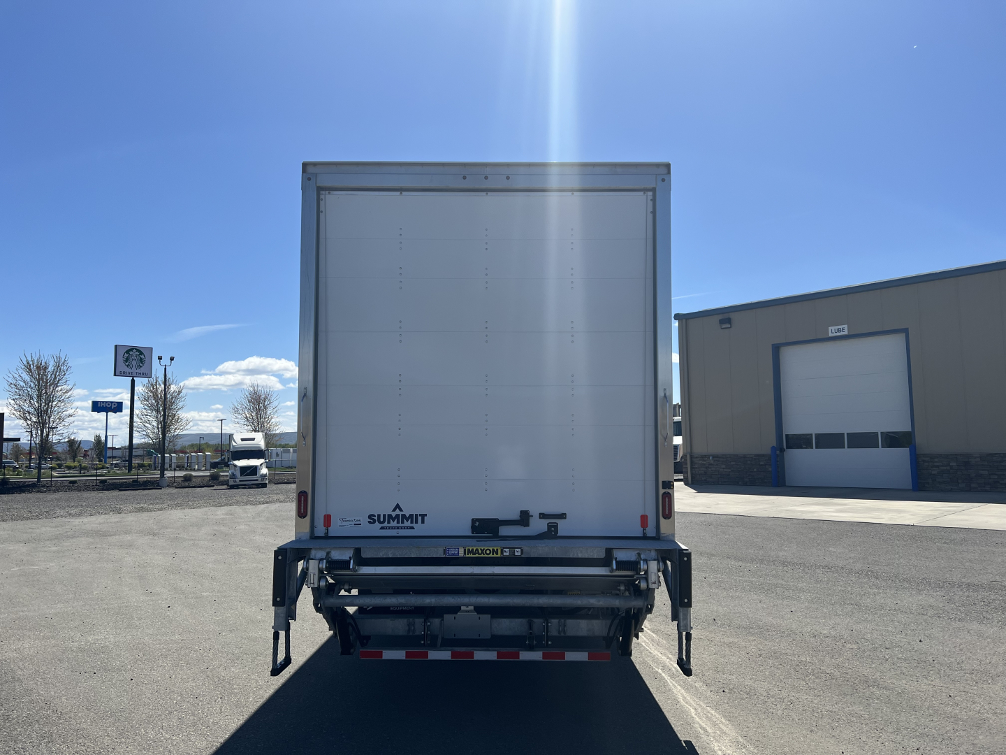 Rear view of a new 2025 Mack MD6 box truck showing the back doors, rear bumper, and Summit trailer branding on the lower left of the cargo door.