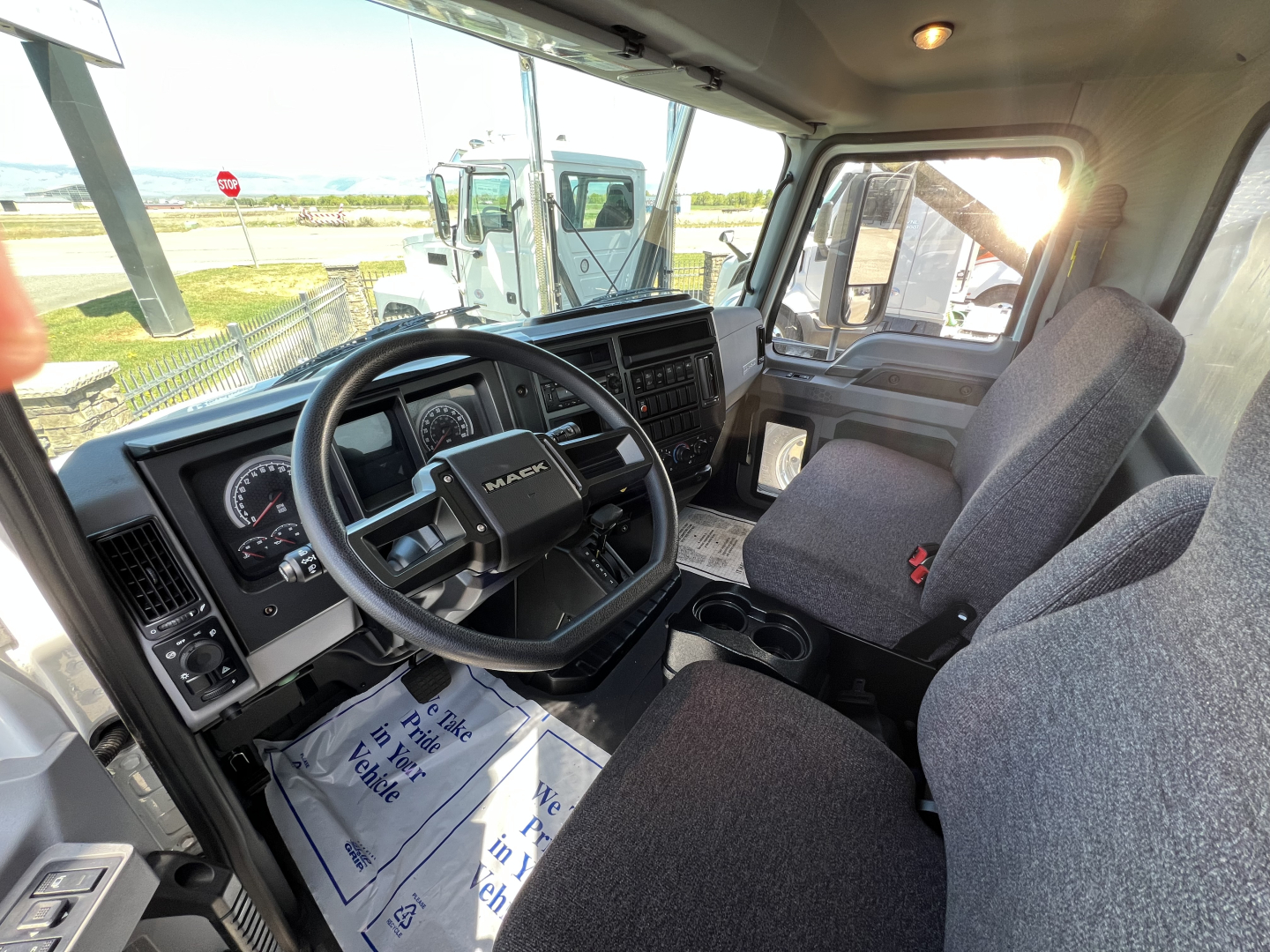 Mack MD6 cab interior showing steering wheel, dashboard gauges, driver seat, and passenger seat with center console.