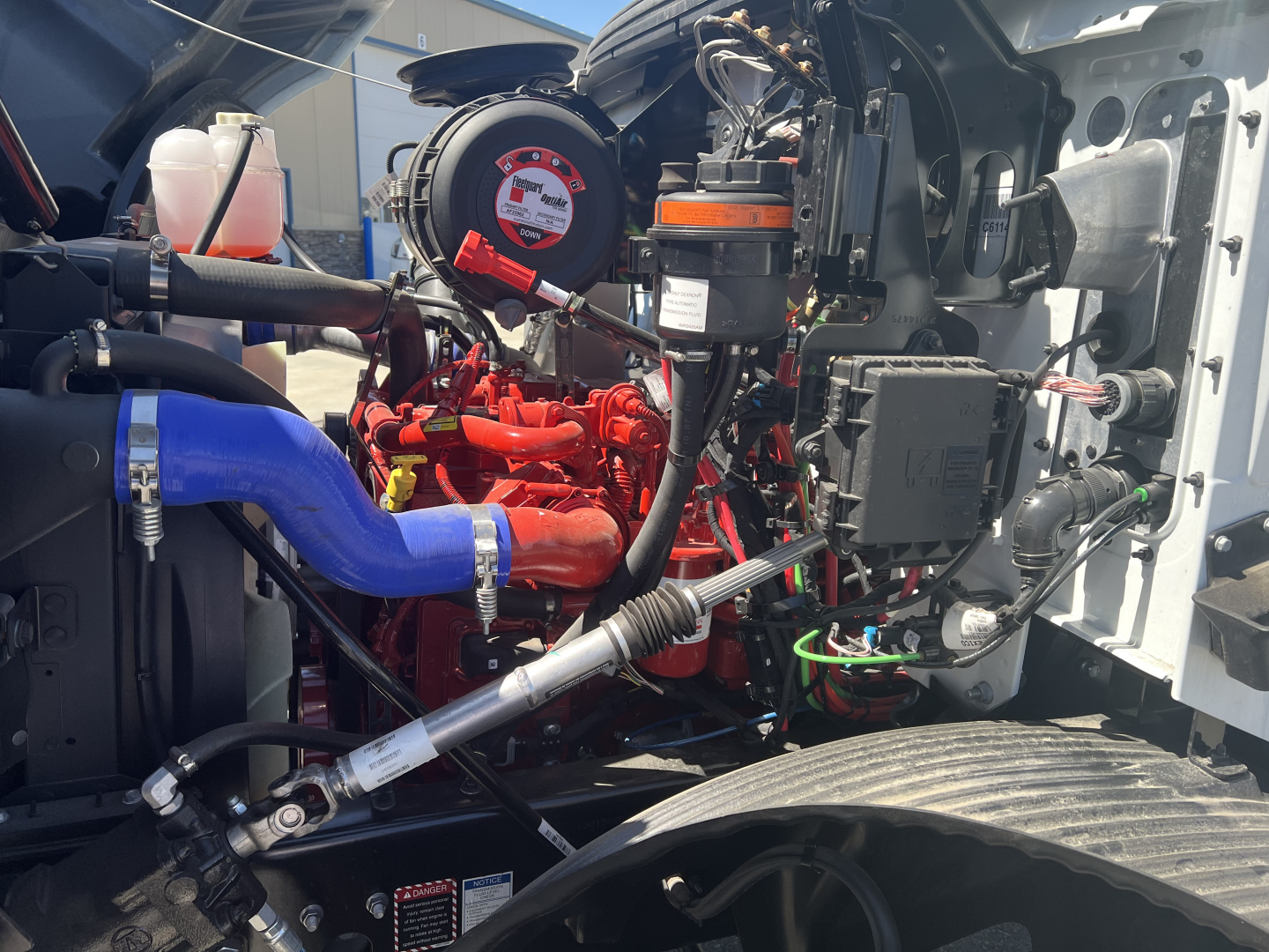 Mack MD6 engine bay showing red engine components, blue hose, and black and silver surrounding hardware