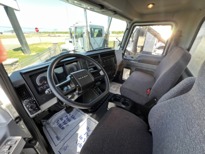 Mack MD6 cab interior showing steering wheel, dashboard gauges, driver seat, and passenger seat with center console.