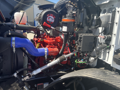 Mack MD6 engine bay showing red engine components, blue hose, and black and silver surrounding hardware