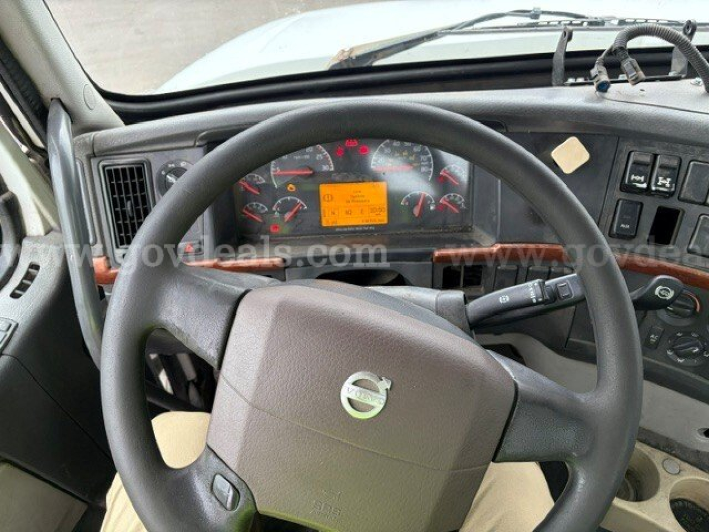 Volvo VHD steering wheel and dashboard view showing orange warning label on instrument cluster and circular gauges.
