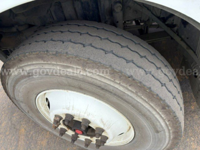 Front wheel and tire of a 2011 Volvo VHD trucks showing dual rear or single front wheel hub with lug nuts and worn tread.