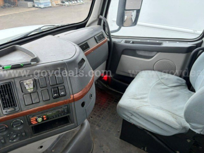 Volvo VHD cabin dashboard and driver seat with controls, gray interior, wood trim accents, steering wheel, center console, and passenger seat visible.