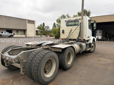 Truck tractor chassis with rear dual rear axles and fifth wheel plate, cab with sleeper, Volvo VHD style, visible labels and windows, used condition.