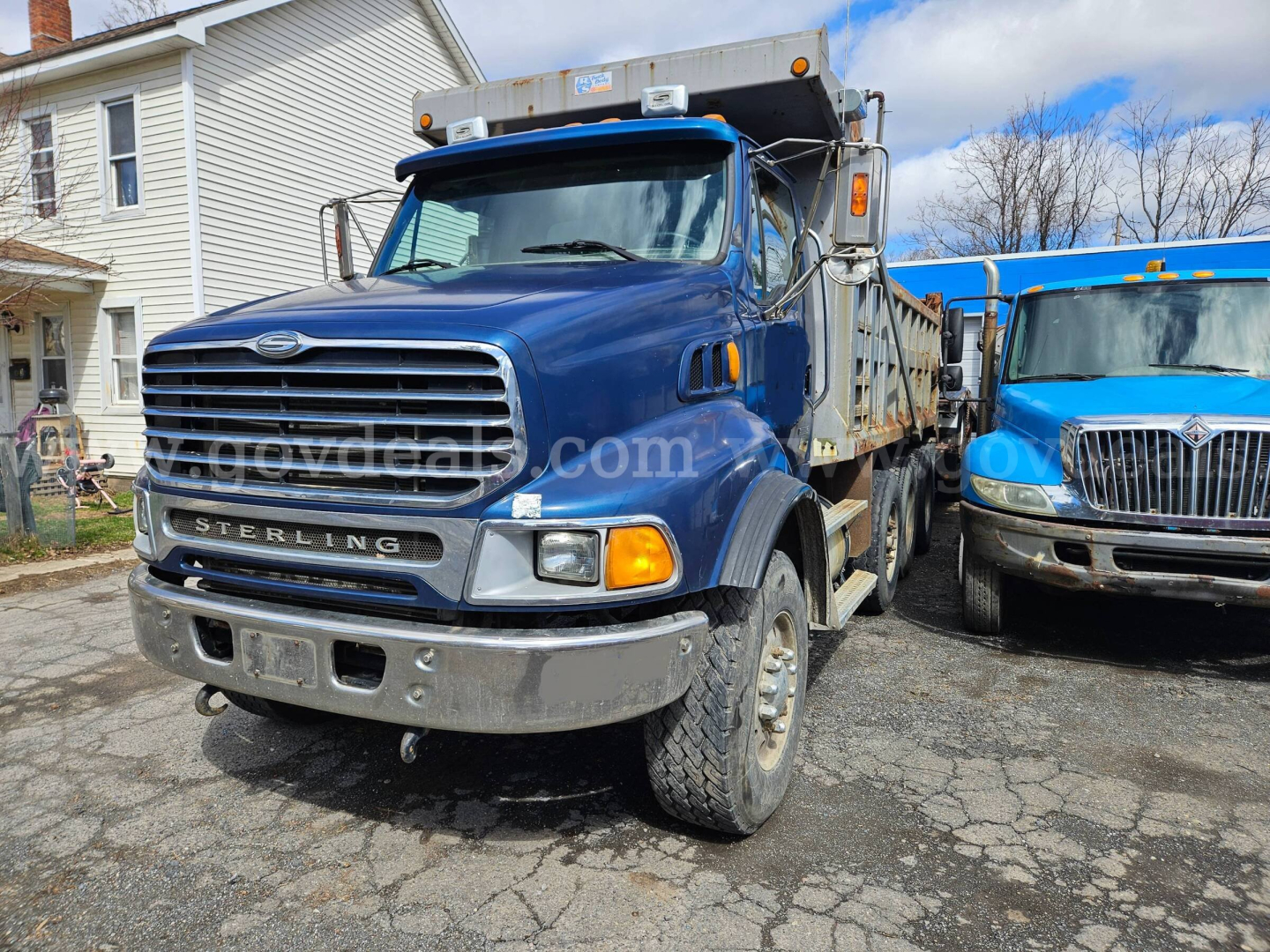 Dump truck showing Sterling LT9500 cab and front grille with blue paint and chrome bumper.