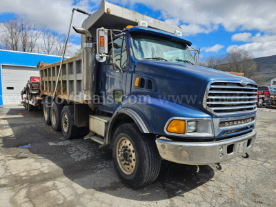 Truck image showing a blue Sterling LT9500 dump truck with a large chrome grille and tip bed, side mirrors, and front bumper.