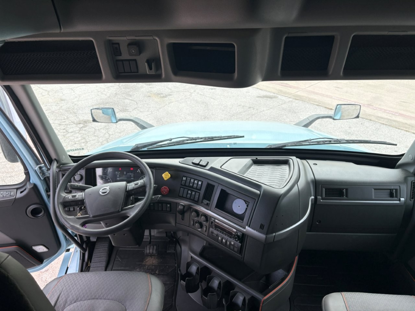 Cab interior of a Volvo VNL64T760 truck showing steering wheel, dashboard, and control panels in the driver’s area.