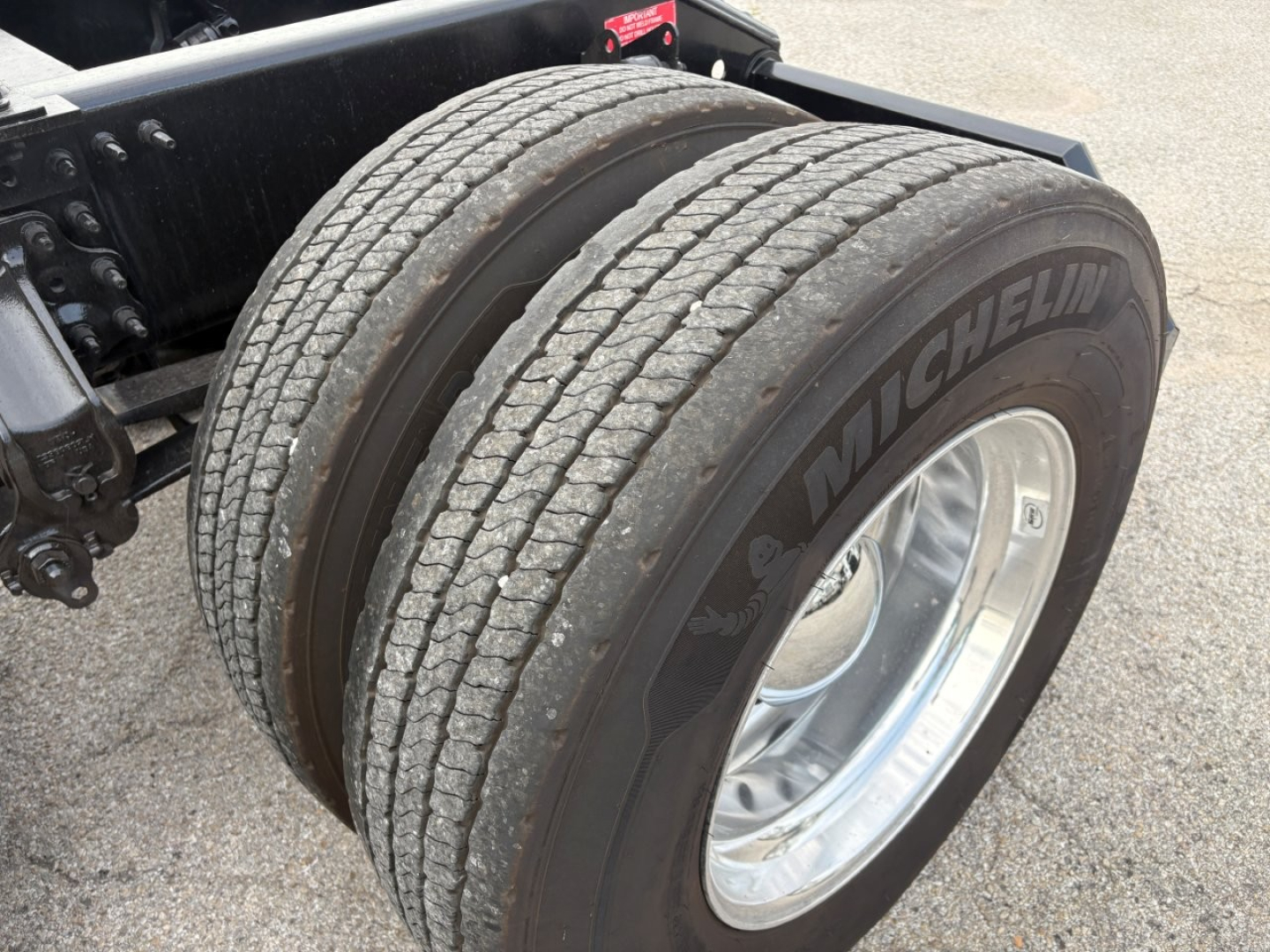 Dual rear wheels with Michelin tire brand on heavy-duty Volvo VNL64T760 truck chassis showing duals and alloy wheel.